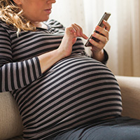 Pregnant woman browsing on a smart device.